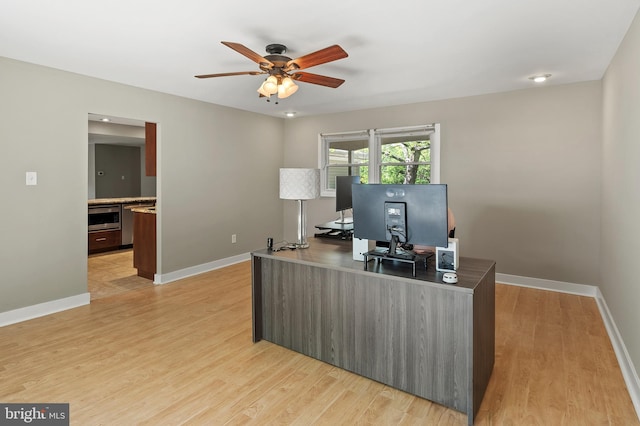 office with baseboards, a ceiling fan, and light wood-style flooring