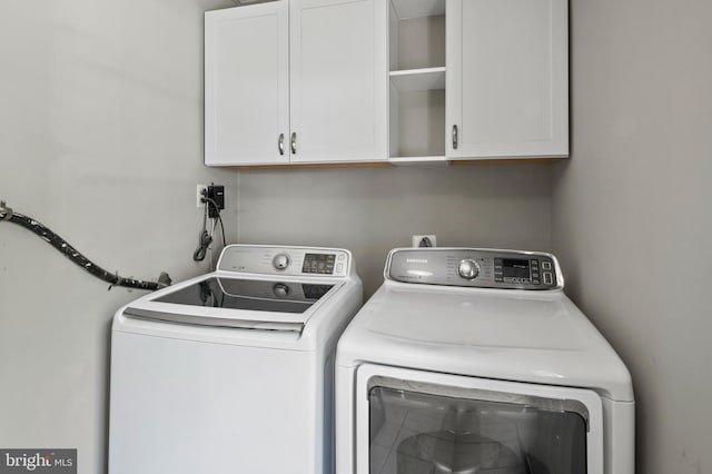 laundry room featuring separate washer and dryer and cabinet space