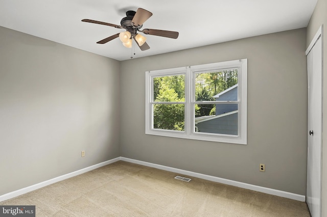 empty room featuring light colored carpet, baseboards, visible vents, and a ceiling fan