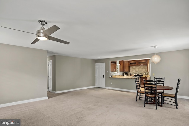 dining area featuring baseboards, ceiling fan, and light carpet