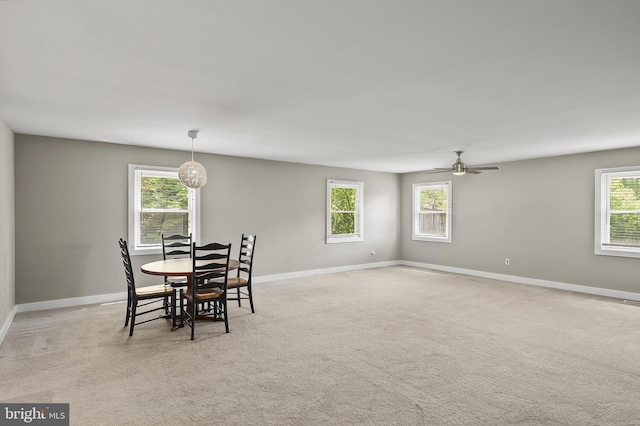 dining area featuring baseboards, ceiling fan, and light carpet