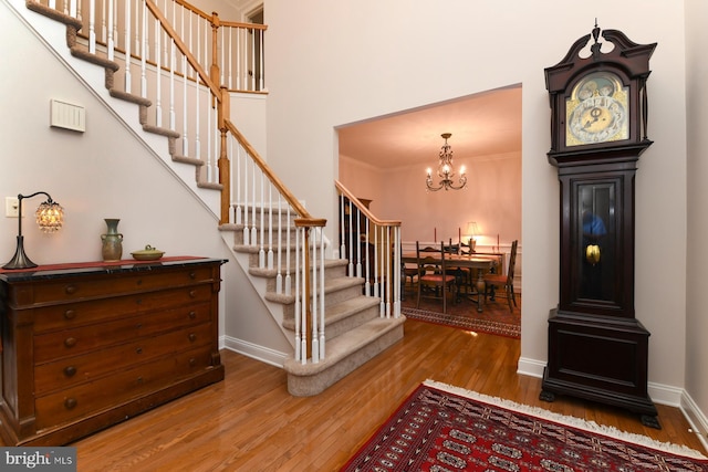 stairway featuring wood finished floors, a chandelier, baseboards, and ornamental molding