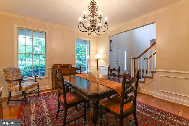 dining area with hardwood / wood-style floors, a chandelier, stairs, crown molding, and a wainscoted wall
