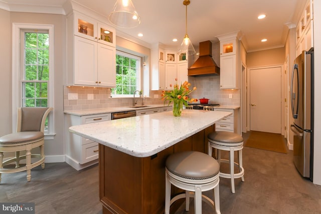 kitchen featuring freestanding refrigerator, custom range hood, a sink, white cabinets, and a kitchen island