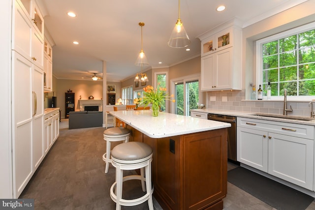 kitchen featuring dishwasher, a sink, open floor plan, a fireplace, and ceiling fan
