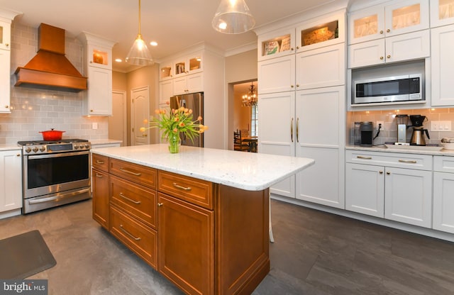 kitchen with stainless steel appliances, wall chimney range hood, tasteful backsplash, white cabinets, and pendant lighting