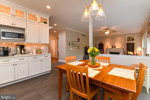 dining room featuring ceiling fan, crown molding, a fireplace, and recessed lighting