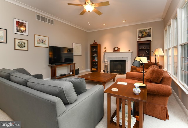 carpeted living area with a fireplace, ceiling fan, baseboards, and crown molding