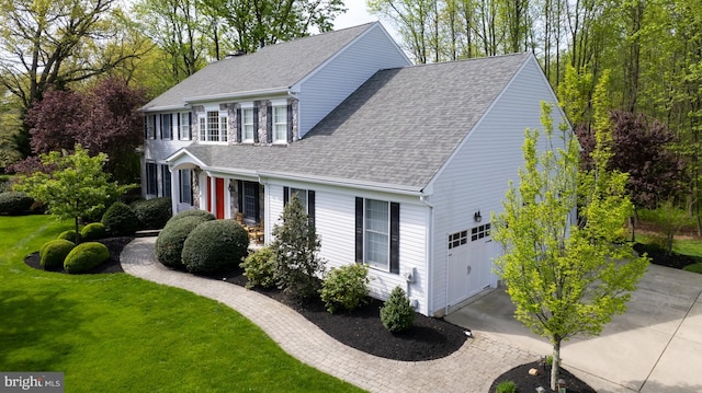 view of front of home with a shingled roof, concrete driveway, a garage, and a front lawn