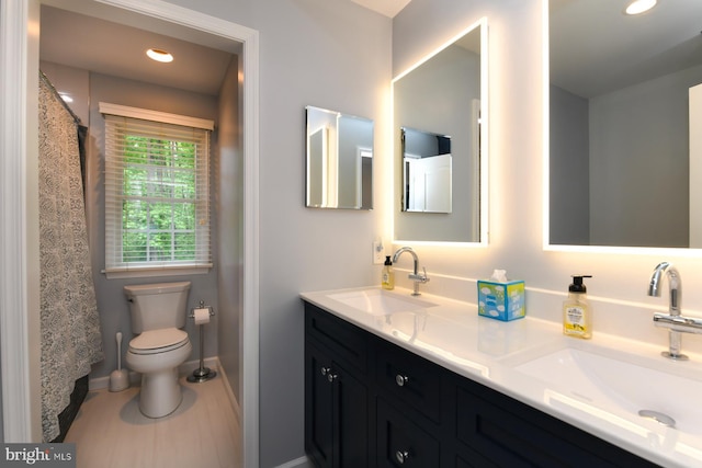 full bathroom featuring baseboards, toilet, double vanity, and recessed lighting