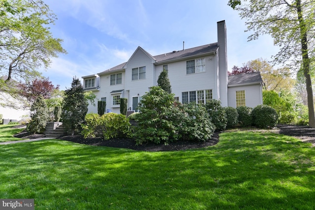 back of property with a chimney and a lawn