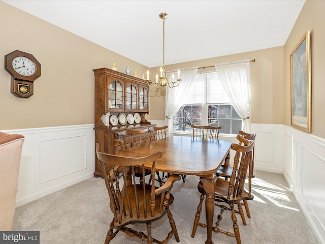 dining room with a wainscoted wall, a decorative wall, and a chandelier