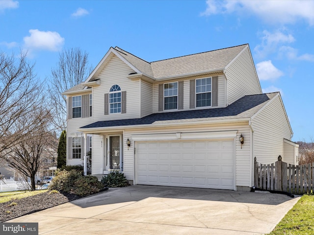 traditional-style home with fence, an attached garage, concrete driveway, and roof with shingles
