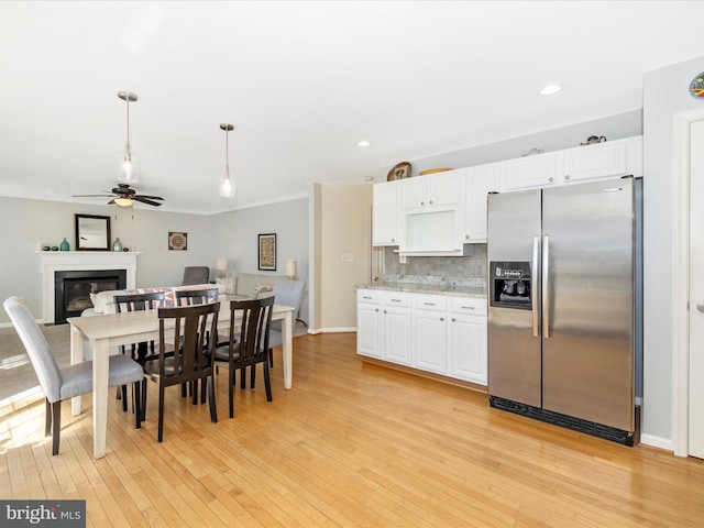 kitchen featuring stainless steel fridge, white cabinets, a ceiling fan, and light wood-style flooring