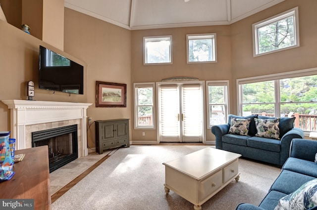 living room with high vaulted ceiling, carpet floors, baseboards, and a tile fireplace