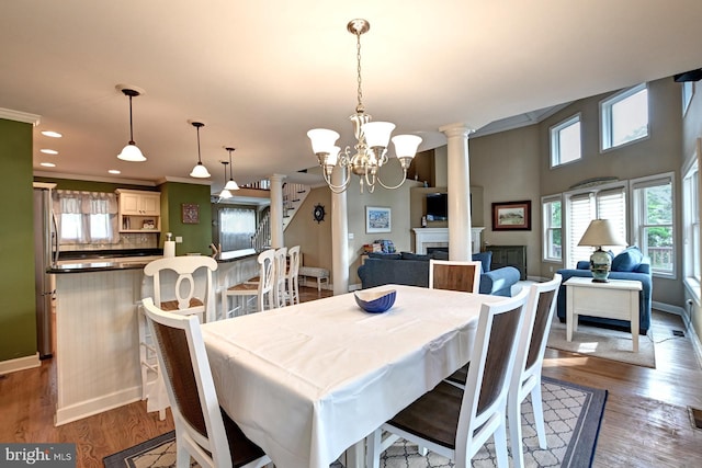 dining space featuring ornate columns, baseboards, a notable chandelier, and wood finished floors