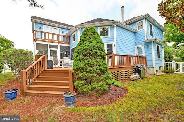 rear view of house with a yard, a deck, fence, and a sunroom