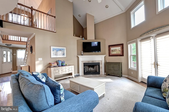 living area with baseboards, high vaulted ceiling, and a tile fireplace