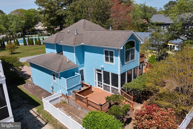 rear view of house with fence, a shingled roof, a sunroom, and a wooden deck