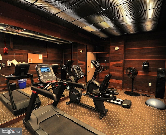 workout area featuring carpet flooring and wood walls