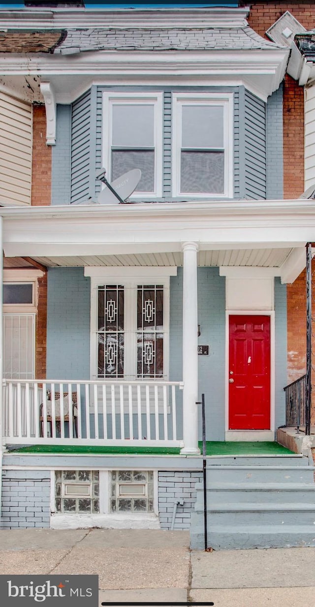 property entrance featuring covered porch and brick siding