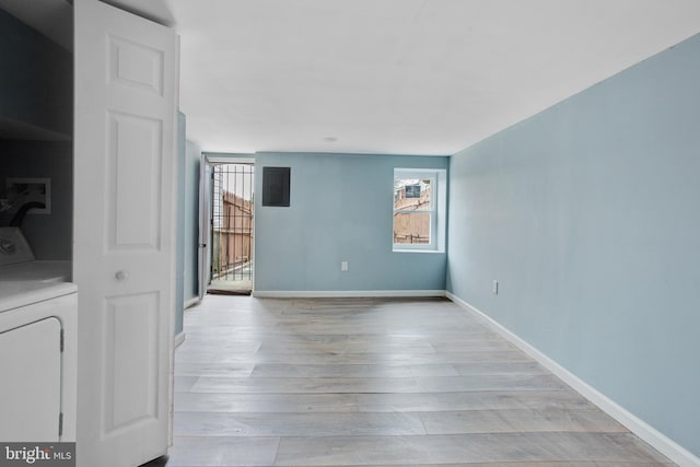 empty room with washer / clothes dryer, baseboards, and light wood-style floors