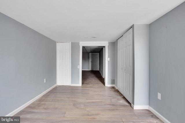 unfurnished room with baseboards and light wood finished floors