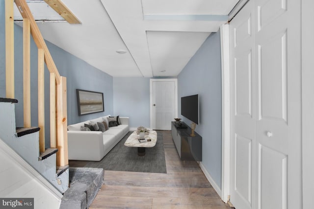 living room with baseboards, wood finished floors, and stairway