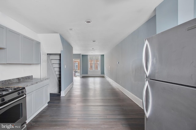 kitchen featuring light countertops, baseboards, appliances with stainless steel finishes, and dark wood finished floors