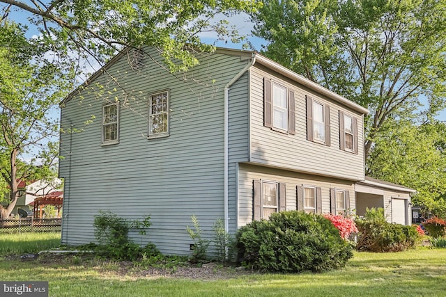 view of side of property featuring a garage, fence, and a yard