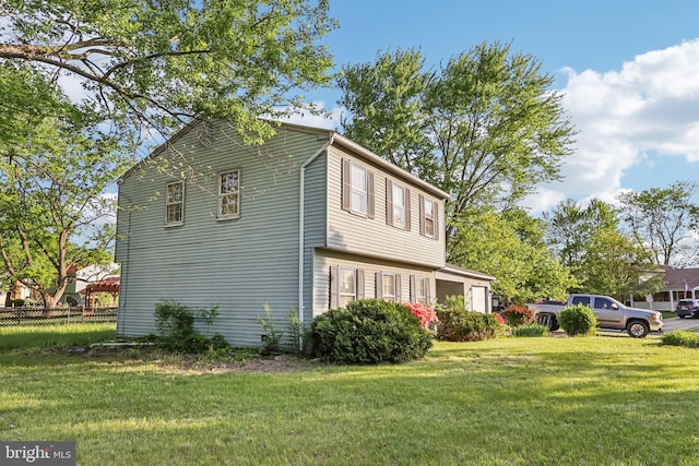 view of home's exterior with fence and a yard