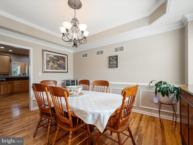 114 New Market Dr, Stephens City, VA 22655 - dining room featuring light wood-style floors, a chandelier, crown molding, a wainscoted wall, and a raised ceiling