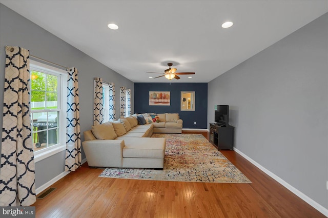 living area featuring baseboards, a ceiling fan, visible vents, and wood finished floors