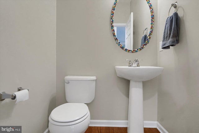 bathroom with a sink, toilet, baseboards, and wood finished floors