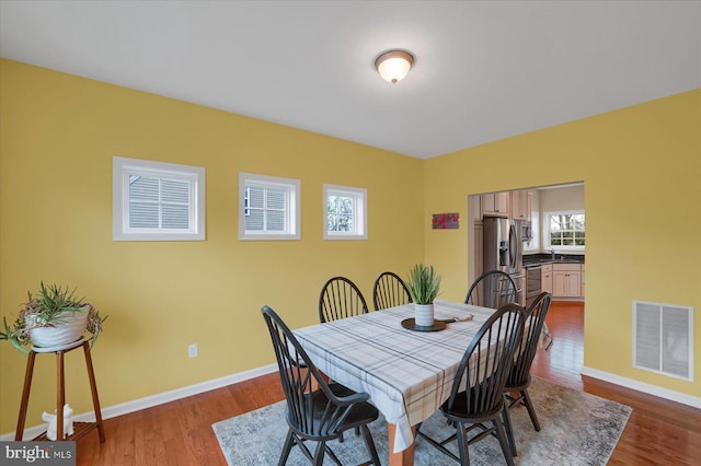 dining room with a wealth of natural light, dark wood-type flooring, and visible vents