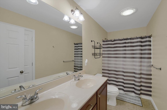 bathroom with double vanity, tile patterned floors, toilet, and a sink