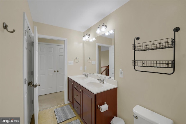 bathroom with toilet, tile patterned flooring, double vanity, and a sink