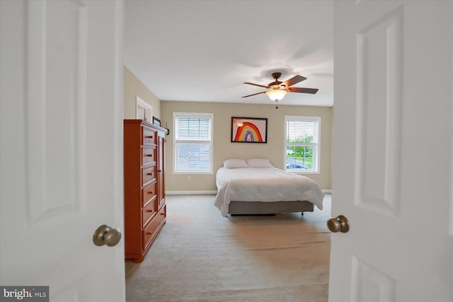 bedroom featuring light colored carpet, baseboards, and ceiling fan
