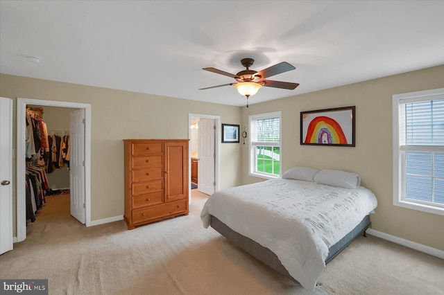 bedroom with baseboards, a spacious closet, a closet, and light colored carpet