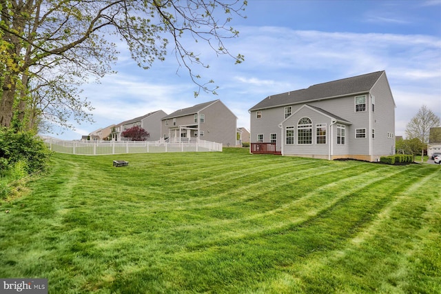rear view of house with a yard, fence, and a deck