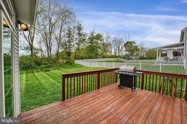 wooden terrace featuring a yard, grilling area, and a fenced backyard