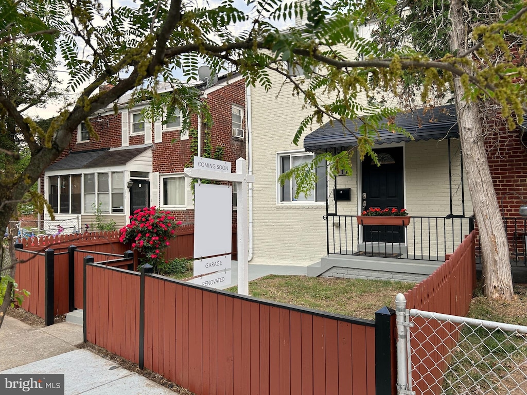 view of front of property with covered porch, brick siding, a fenced front yard, and a gate
