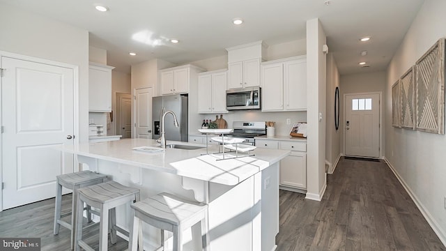 kitchen with light countertops, stainless steel appliances, dark wood-style flooring, and an island with sink