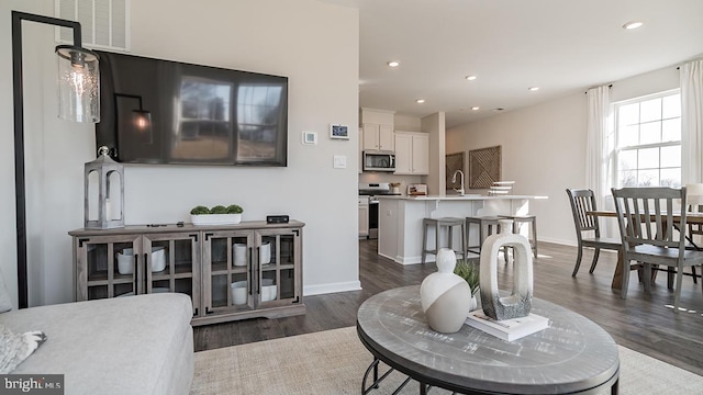 living room with recessed lighting, baseboards, dark wood-style flooring, and visible vents