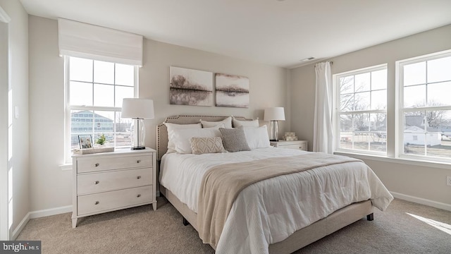 bedroom featuring light colored carpet, baseboards, and multiple windows