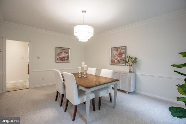 dining room with ornamental molding, light carpet, and baseboards