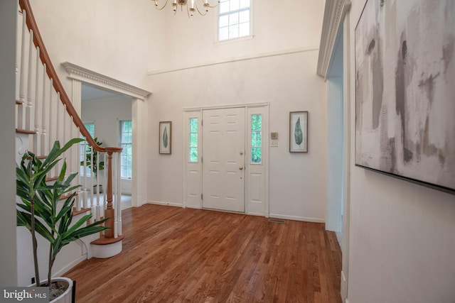 foyer featuring stairway, a chandelier, wood finished floors, a towering ceiling, and baseboards