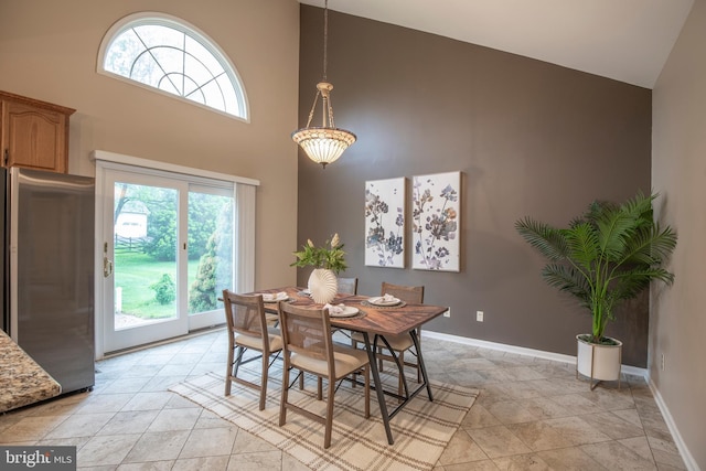 dining space featuring high vaulted ceiling and baseboards