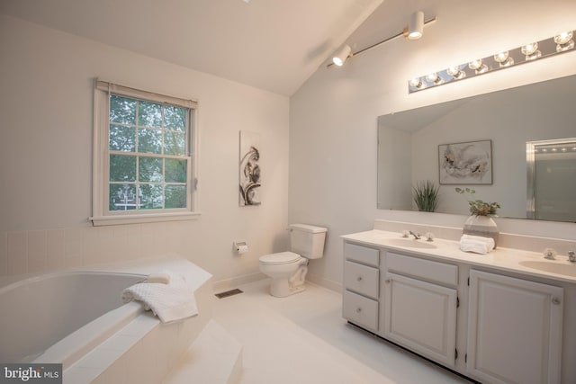bathroom featuring a bath, double vanity, toilet, lofted ceiling, and baseboards