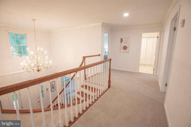 corridor with an upstairs landing, a chandelier, carpet floors, ornamental molding, and baseboards